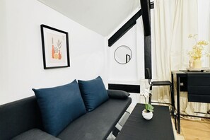Ein modernes Wohnzimmer mit einer Couch, einem kleinen Tisch mit einer Vase, einem Spiegel und einem gerahmten Bild an der Wand.