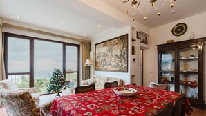 Ein Esszimmer mit einem großen Tisch, Stühlen, einem Weihnachtsbaum und Blick durch große Fenster.