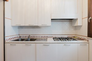A kitchen with white cabinets, a gas stove, a sink, and a decorative backsplash. - Ciciliana: Tranquility and Panoramic Views in Sicily (Valderice)