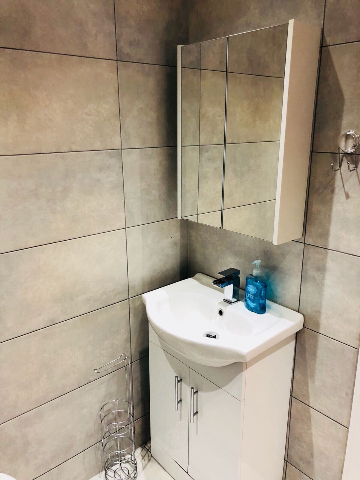 Une salle de bain avec un lavabo blanc, un miroir au-dessus et un meuble en dessous.