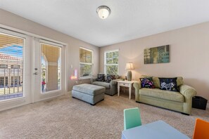 A living room with a sofa, ottoman, and a table with a lamp. - Private *Pool*Spa*Close to Disney *Sleeps 12* (Davenport)