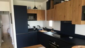 Eine moderne Küche mit Holzschränken, einer schwarzen Arbeitsplatte und einem eingebauten Backofen.