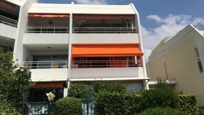 Ein mehrstöckiges Gebäude mit Balkonen und orangefarbenen Markisen.