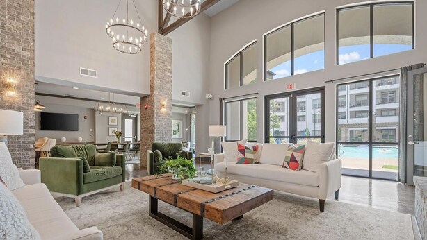 A spacious living area with a high ceiling, large windows, and a view of a swimming pool. - Landing | Spectacular 1BD, Gym, Courtyard (Little Rock)