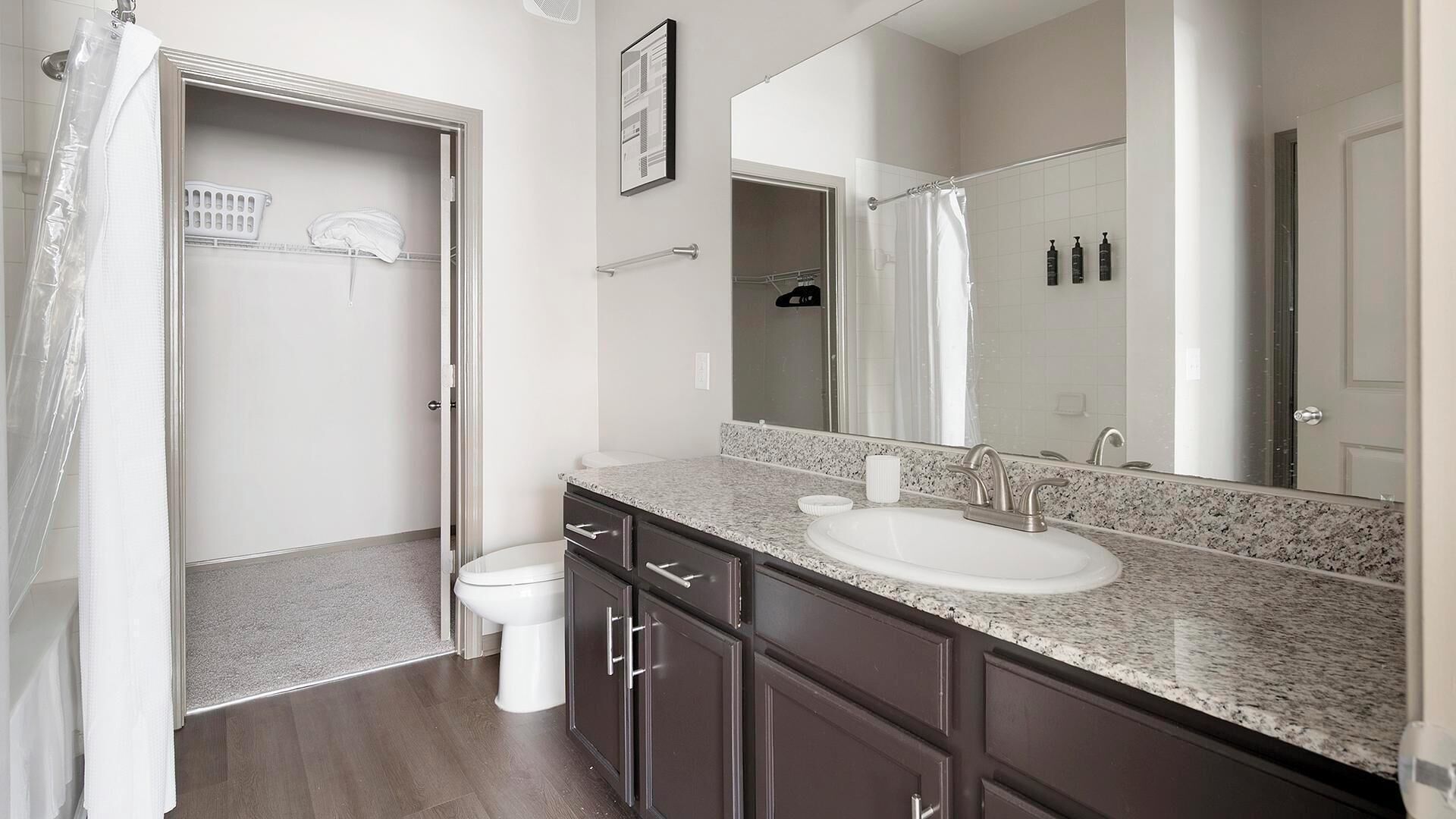 Un bagno moderno con il water bianco, un lavandino con uno specchio grande e una zona doccia.