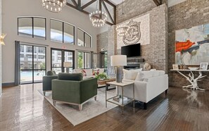 A spacious lobby with a high ceiling, a fireplace, and a large window overlooking a pool. - Landing | Incredible 2BD, Gym, Yoga Studio (Little Rock)