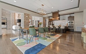 A modern kitchen with a central island, bar stools, and a dining area with a colorful rug. - Landing | Amazing 2BD, Yoga Studio, Clubhouse (Little Rock)