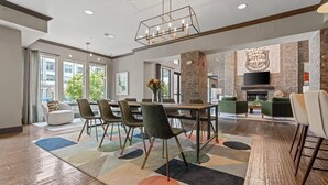 A modern dining area with a large table and chairs, a fireplace, and a view of the outdoors.