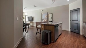 Uma cozinha moderna com máquina de lavar louça embutida, área de refeições com cadeira e mesa, e uma porta escura.