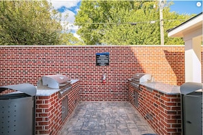 An outdoor barbecue area with brick walls and two grills. - Landing | Stylish 1BD, Gym, Clubhouse (Memphis)