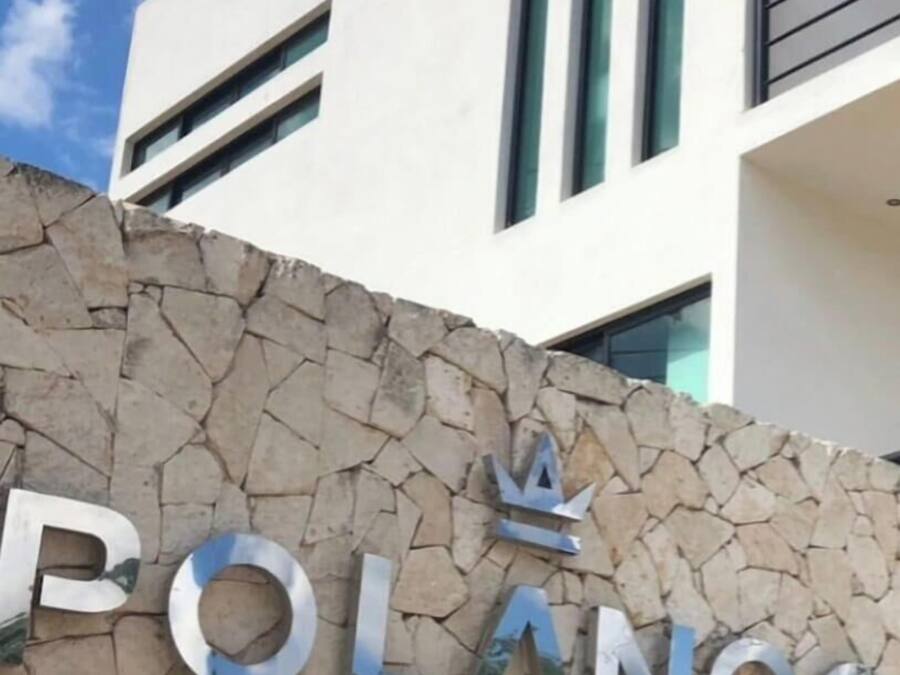 A building with a sign that reads "POLANCO DEPARTAMENTOS" on a stone wall.