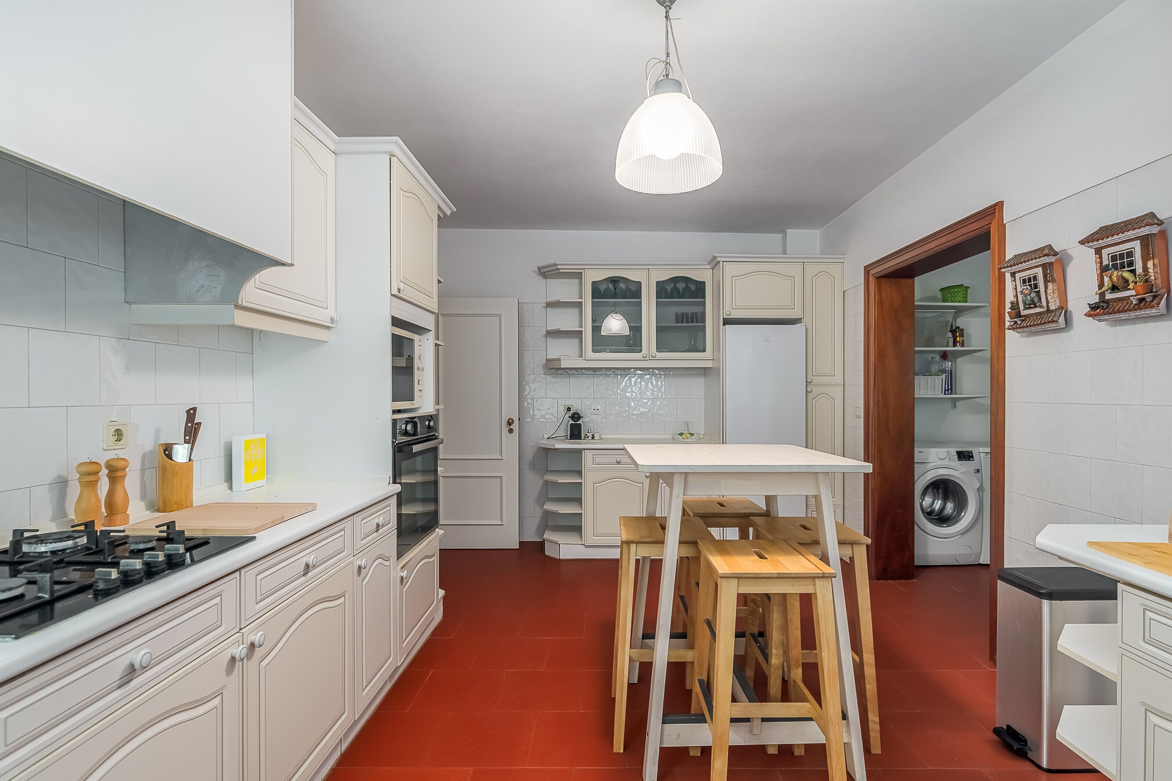 A kitchen with white cabinets, a gas stove, a wooden table, and a washing machine.