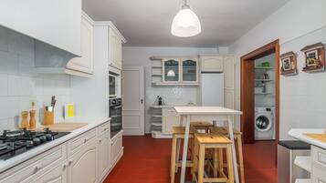 A kitchen with white cabinets, a gas stove, a wooden table, and a washing machine.