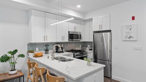 Una cocina moderna con armarios blancos, electrodomésticos de acero inoxidable y encimera de mármol.
