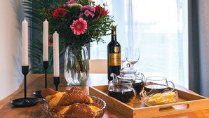 Ein Holztisch mit einer Glasvase voller Blumen, Kerzen, einer Weinflasche und Gläsern.