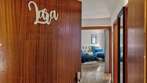 Eine Holztür mit einer Namensschild, auf der "Lara" steht, führt in ein Schlafzimmer mit einem Bett, Nachttischen und einem gerahmten Bild an der Wand.