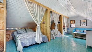 Una habitación con dos camas, un sofá y techo de madera.