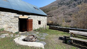 Un edificio de piedra con techo metálico, una puerta de madera y un banco de piedra.