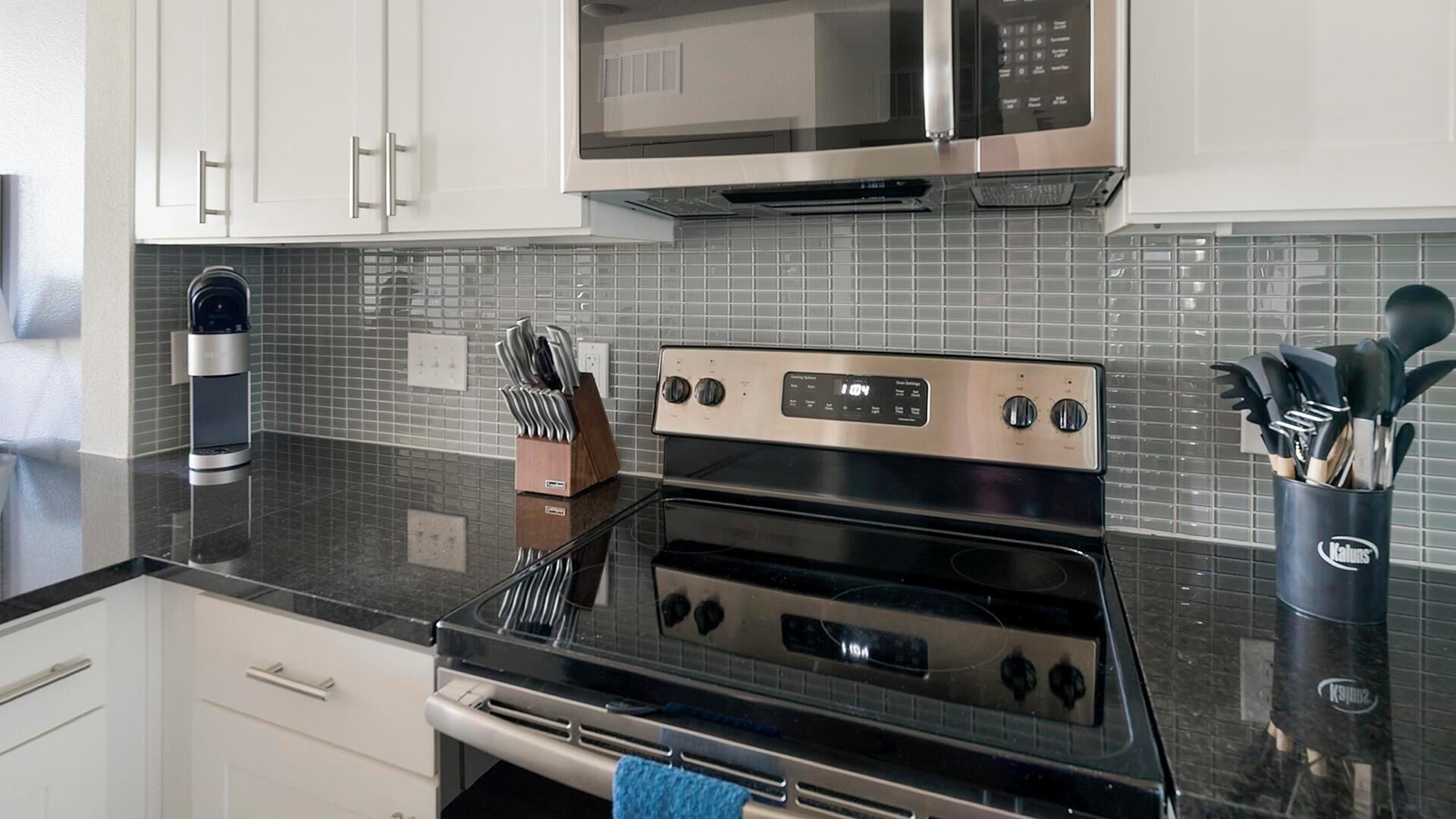 A kitchen with a stainless steel oven, a microwave, and a tiled backsplash.