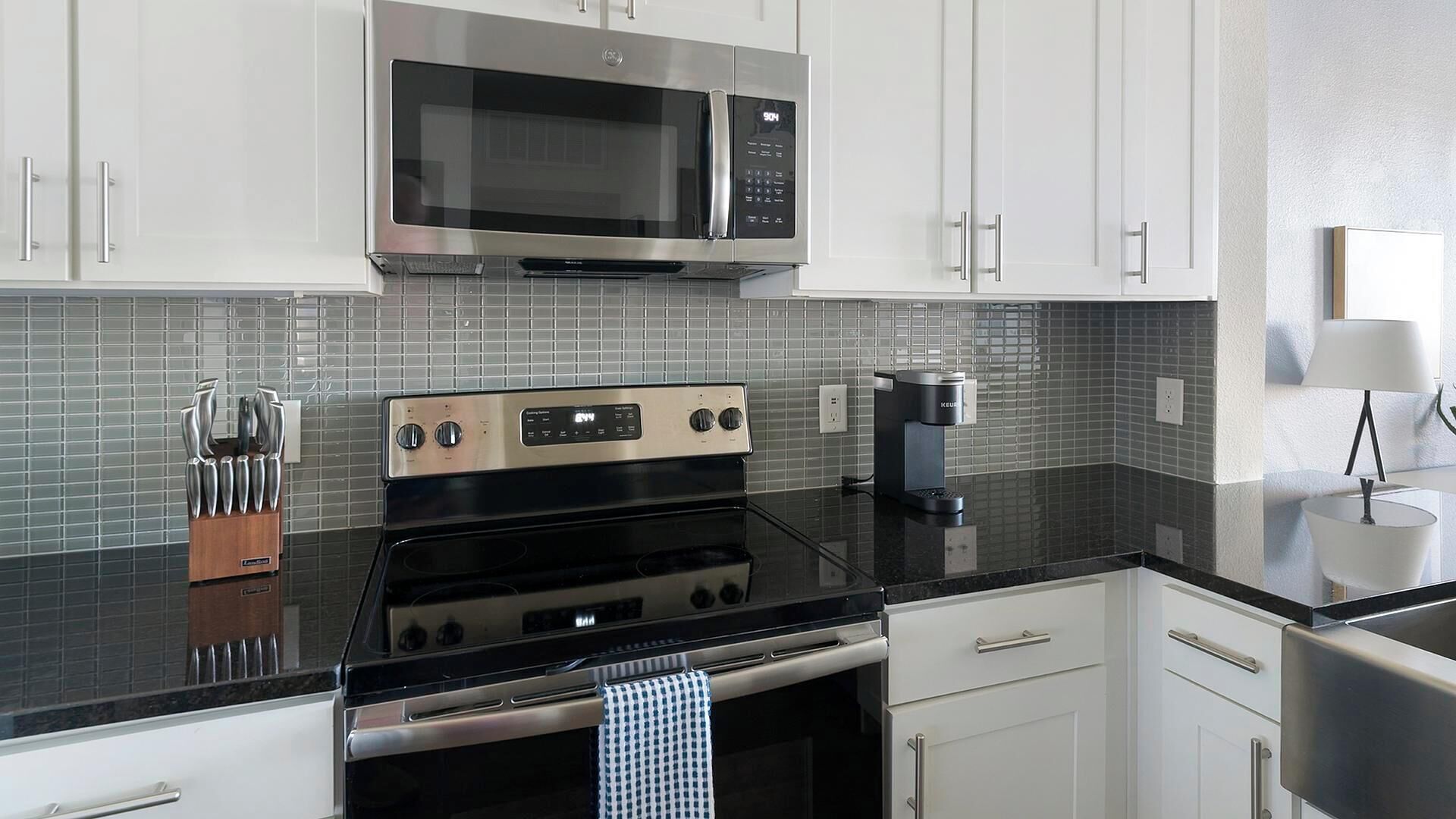 Una cocina moderna con electrodomésticos de acero inoxidable, armarios blancos y un salpicadero de azulejos.