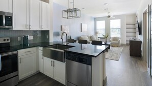 Una cocina moderna con electrodomésticos de acero inoxidable, lavavajillas y un comedor con sofá y una mesa de centro.