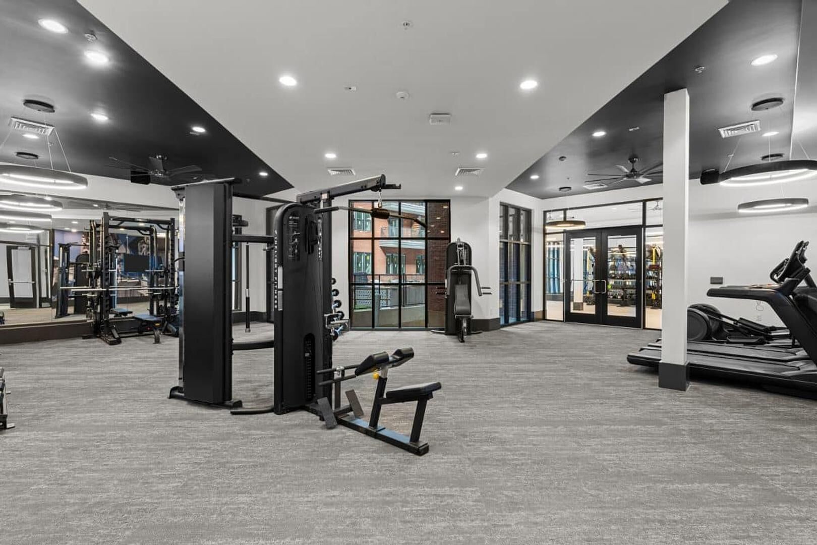 Une salle de sport équipée de divers appareils d’entraînement, notamment un support à squats, un banc de développé couché et des tapis de course.