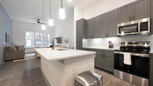 Une cuisine moderne avec des meubles gris, un four à micro-ondes en acier inoxydable et un grand îlot central doté d’un évier.