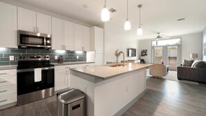 Una cucina moderna con elettrodomestici in acciaio inox, un'isola grande e illuminazione a sospensione.