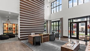 Un'ampia hall dal design moderno, con parete a listelli di legno, reception, zone relax e ampie finestre con vista esterna.