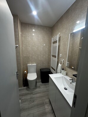 Ein modernes Badezimmer mit Toilette, Bidet, Waschbecken und Spiegel.