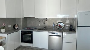 Een moderne keuken met witte kastjes, een vaatwasser, een oven en een spoelbak.