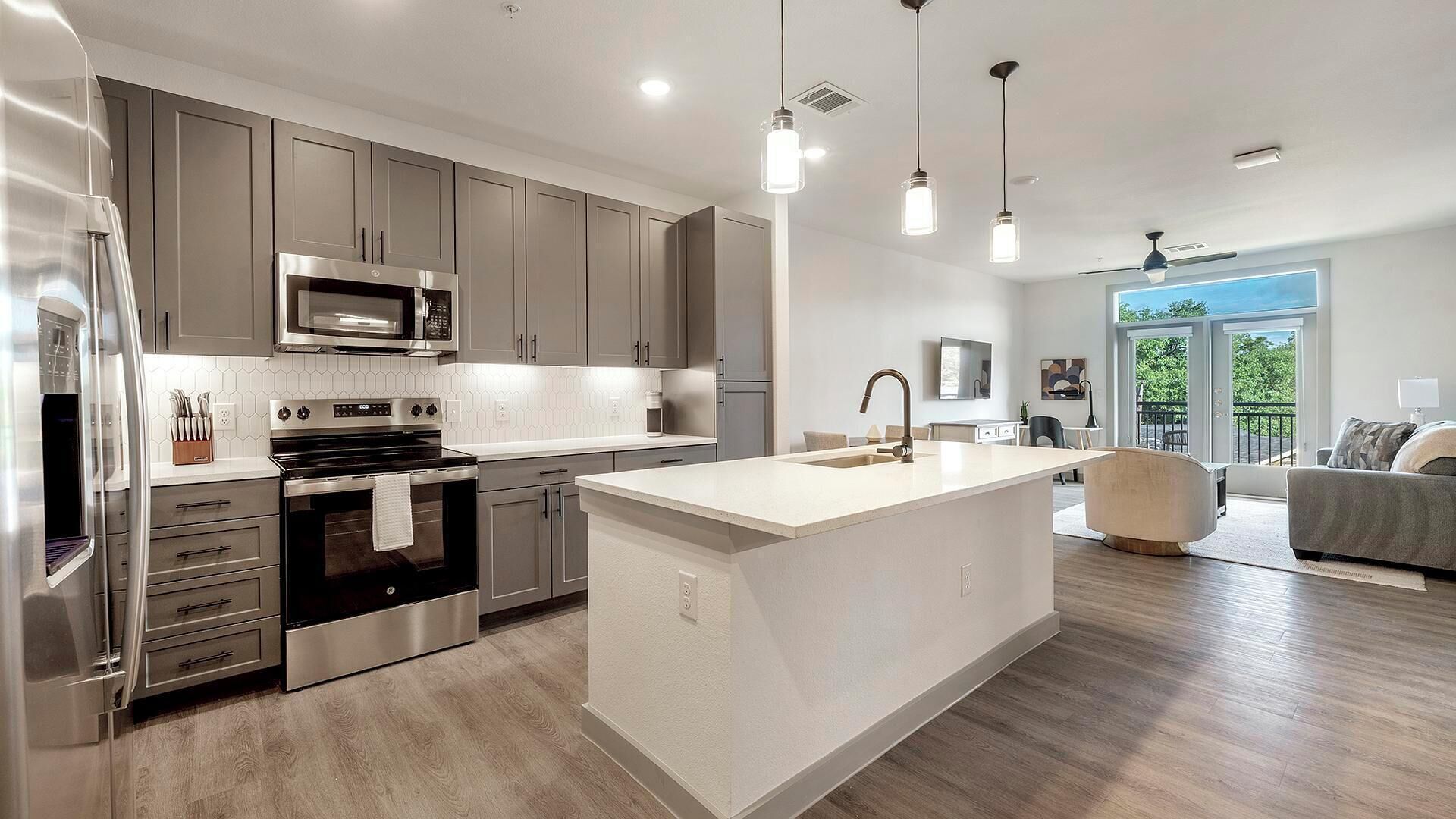 A modern kitchen with stainless steel appliances, a central island, and pendant lighting.