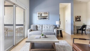 A modern living room with a grey sofa, a coffee table, and a desk with a chair. - Landing | Modern 2BD, Pool (Casas Adobes)