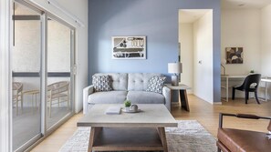 A modern living room with a grey sofa, a coffee table, and a desk with a chair. - Landing | Modern 2BD, Pool (Casas Adobes)