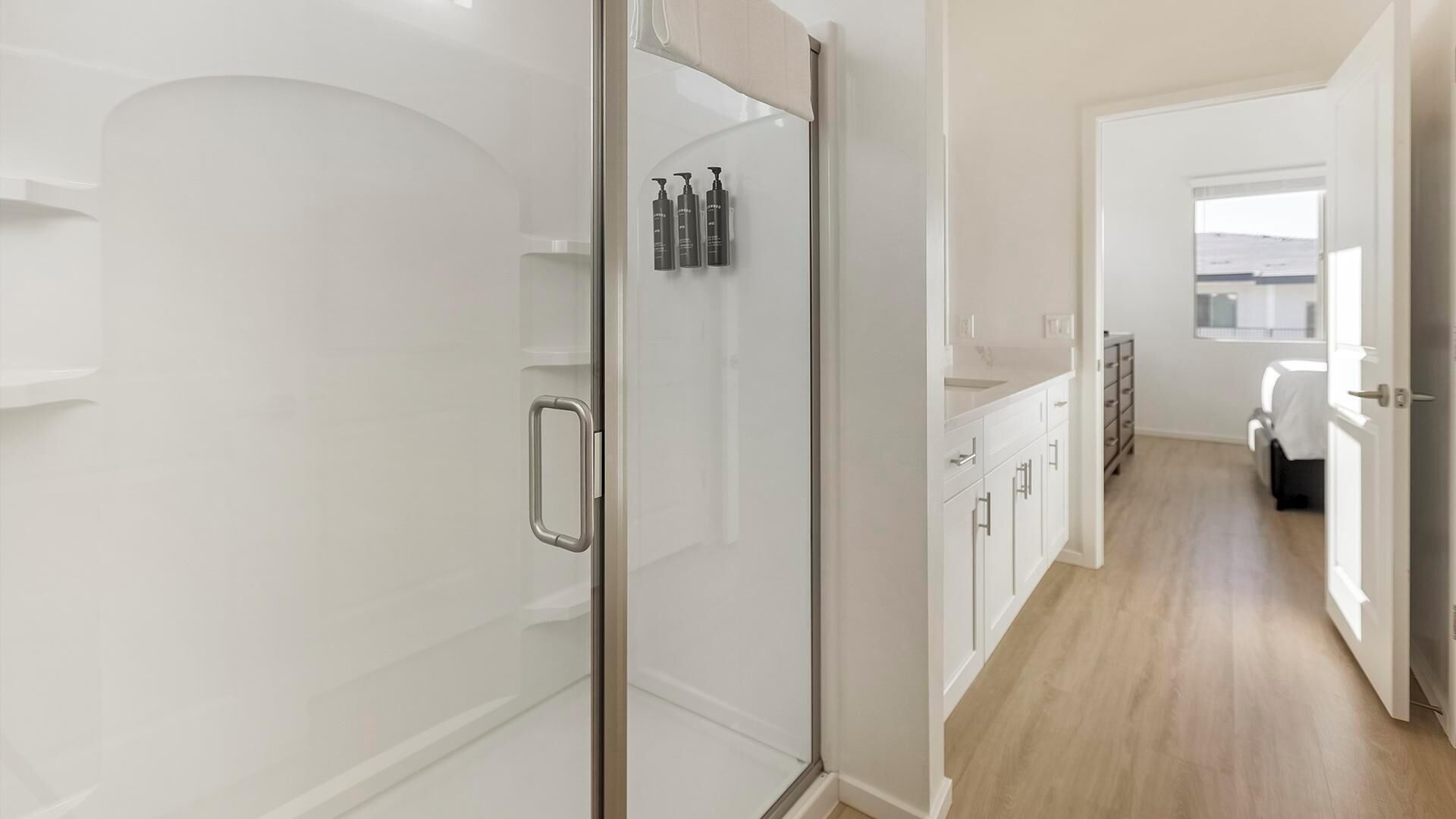 Ein modernes Badezimmer mit einer Duschkabine aus Glas, einem weißen Waschtisch mit Waschbecken und einer begehbaren Dusche mit Pflegeartikeln.