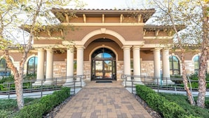 Un edificio con un arco central, columnas y un acceso pavimentado.