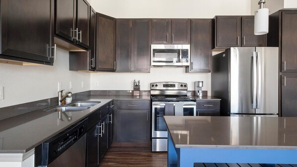 Una cocina moderna con armarios de madera oscura, electrodomésticos de acero inoxidable y una encimera azul.
