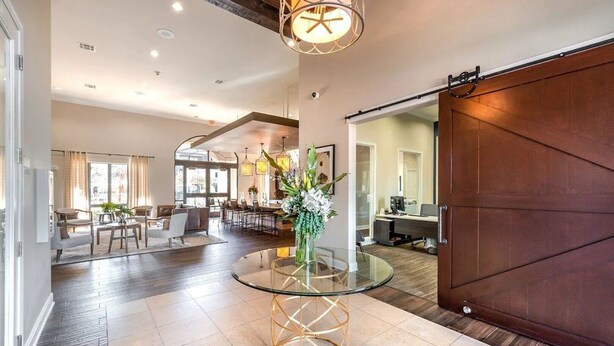 A spacious living area with a glass coffee table, a large wooden door, and a dining area with modern furniture. - Landing | Chic 1BD, Gym (The Woodlands)