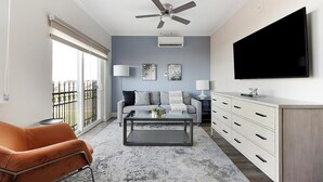 A modern living room with a sofa, coffee table, and TV. - Landing | Amazing 1BD, Gym, Clubhouse (Johnstown)