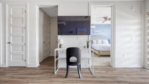 Une chambre à coucher avec un lit, un bureau avec une chaise et un ventilateur de plafond.