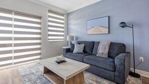 Un salon moderne avec un canapé gris, une table basse et un lampadaire.