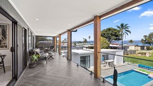 Ein geräumiger Balkon mit Pool, modernen Möbeln und Meerblick.