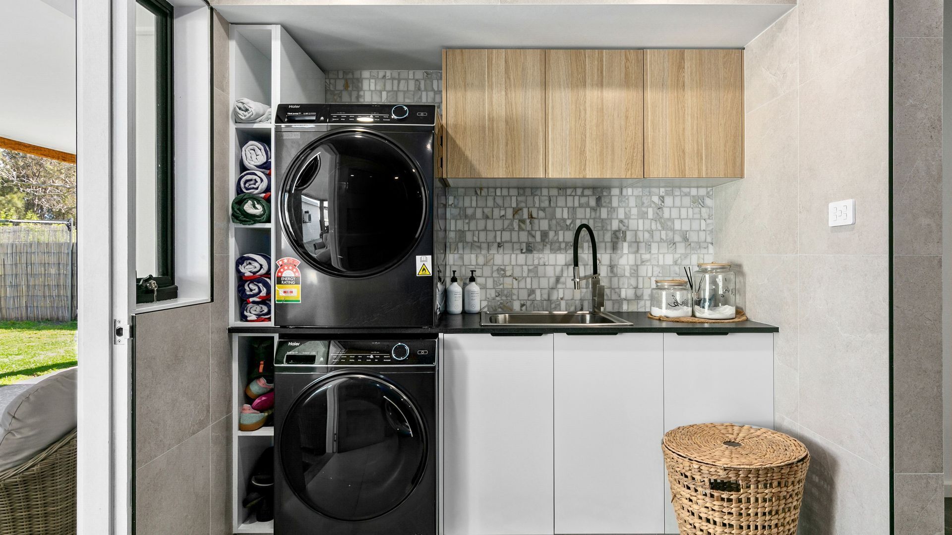 A compact kitchen with a built-in washer and dryer, a sink, and a small storage area with folded towels.