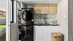 Eine kompakte Küche mit integrierter Waschmaschine und Trockner, einem Spülbecken und einer kleinen Ablage für gefaltete Handtücher.