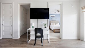 Una camera da letto moderna con un letto, una scrivania con una sedia, una TV e una ventola a soffitto.