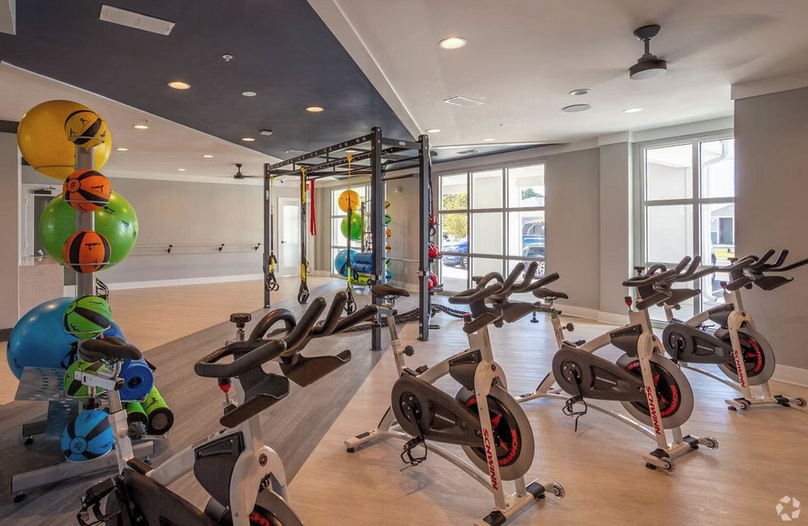 Une salle de sport équipée de vélos d’appartement, d’une barre de traction et de différents ballons d’exercice.