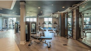 A spacious gym with various exercise equipment, large windows, and a modern design. - Landing | Amazing 2BD, Gym, Game Room (Myrtle Beach)