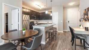 Una cucina moderna con mobili scuri, elettrodomestici in acciaio inossidabile e luci a sospensione.