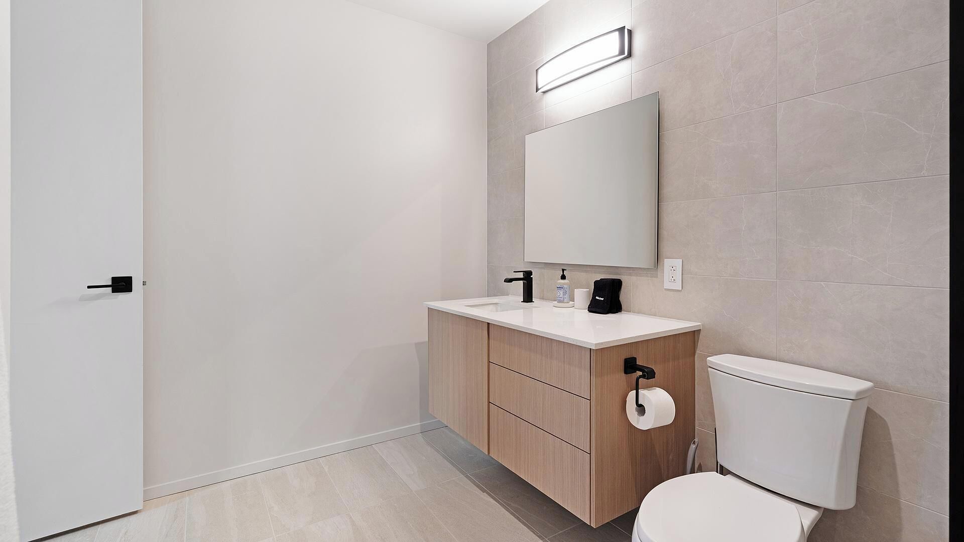 A modern bathroom with a toilet, sink, and mirror.
