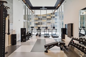 Ein modernes Fitnessstudio mit Laufbändern, Kraftgeräten und Kurzhanteln.